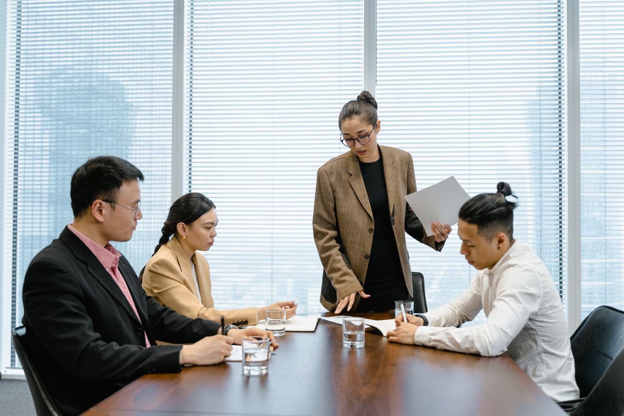 Offerings Business colleagues engaged in a meeting around a wooden table within a modern office.